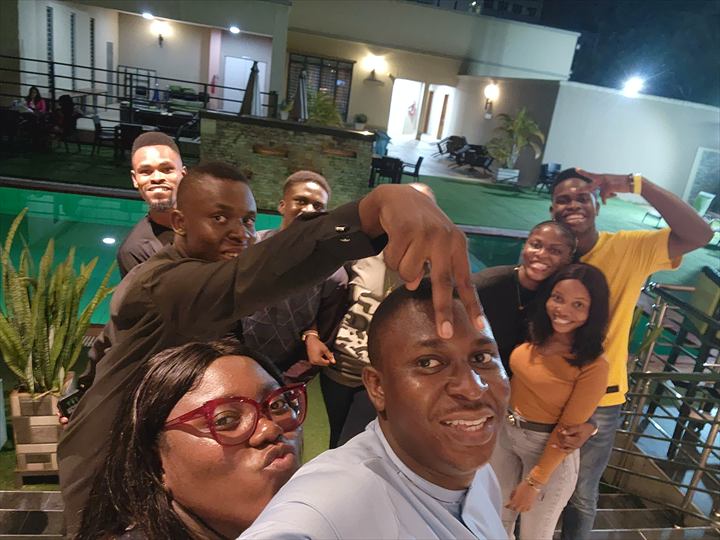 Osaro and Achi sharing a playful poolside group selfie with friends